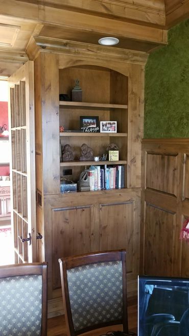 Wooden built-in bookshelf with decorative items and books in a cozy room.