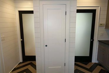 Modern interior with three doors and patterned floor tiles.