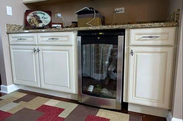 Kitchen area with white cabinets and a wine cooler under granite countertop.