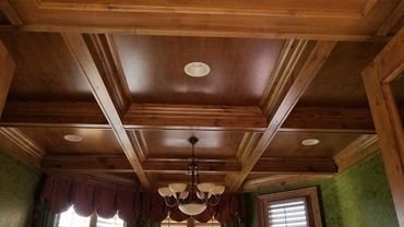 Elegant wooden coffered ceiling with chandelier and recessed lights.