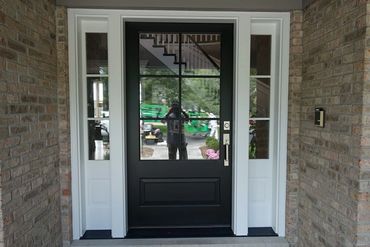 Black front door with glass panels and brick walls on both sides.