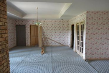 Empty room with floral wallpaper, blue carpet, and wooden doors.