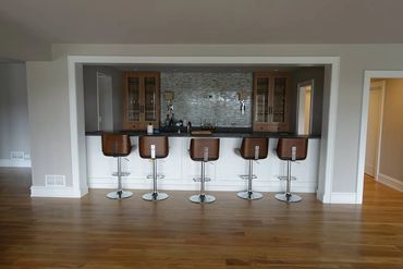 Modern home bar with five wooden stools and a sleek countertop.