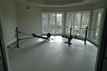 Home gym setup with rowing and weight bench near large windows.