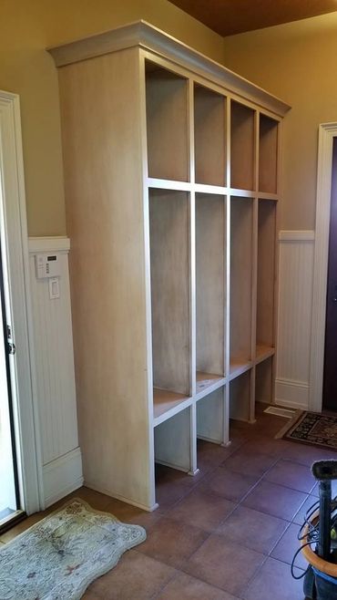 Empty wooden cubby storage unit in a hallway with tile flooring.