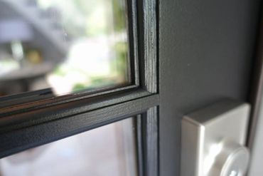 Close-up of a black metal door frame with glass panes and a silver lock.