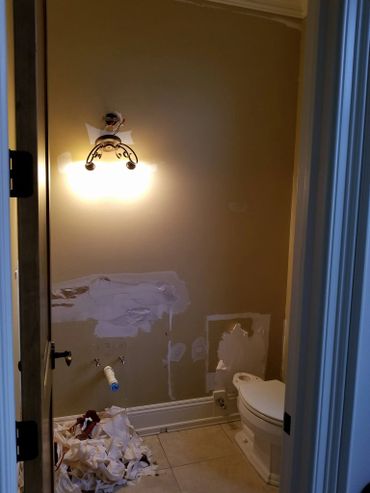 Bathroom under renovation with patched walls and removed fixtures.