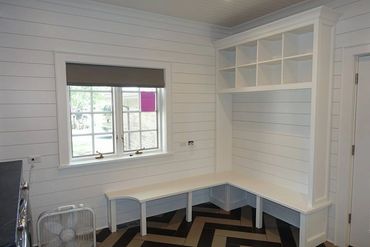 White built-in bench with cubby storage in a bright room with window.