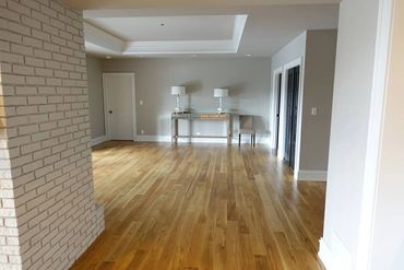 Minimalist room with wooden floor, white brick wall, and simple furniture.