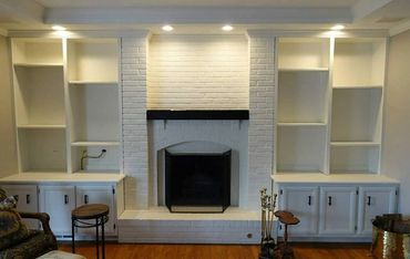 White brick fireplace with built-in shelves and wooden floor.