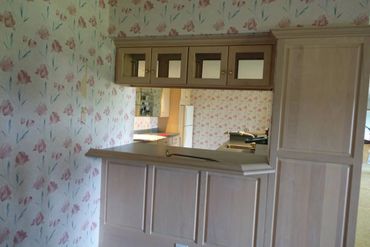 Retro kitchen with floral wallpaper and wooden cabinets.