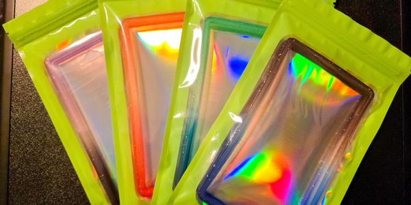 Five colorful phone cases in holographic packaging arranged in a fan shape.