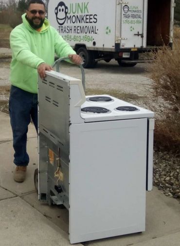 Junk Monkees crew member moving a stove on a hand truck for appliance removal