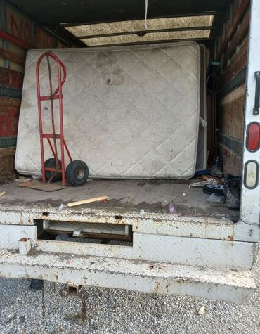 Mattresses loaded in the Junk Monkees truck with a hand truck for removal