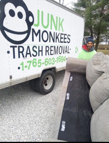 Junk Monkees crew member removing a couch beside the company truck