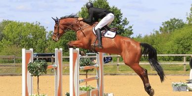 A rider and horse mid-jump over an obstacle during an equestrian event.