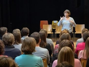 Speaker addressing an audience in a room.