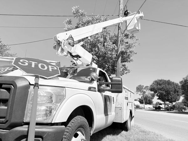 Utility truck with bucket lift near a stop sign on the side of the road.