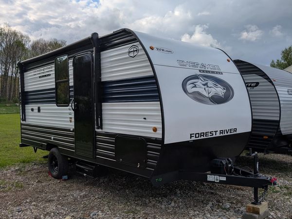 Black and white Forest River Cherokee travel trailer parked on gravel.