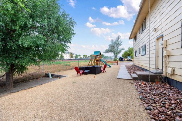 Backyard with playset and seating area beside house.