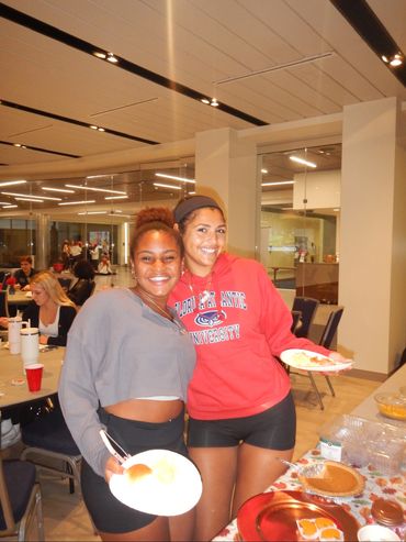 Two girls holding food with their arms around each other.