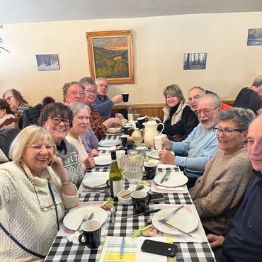 Group of elderly friends enjoying a meal together at a checkered table.