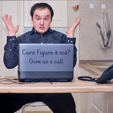 Man looking confused and frustrated while using a laptop at a kitchen table.