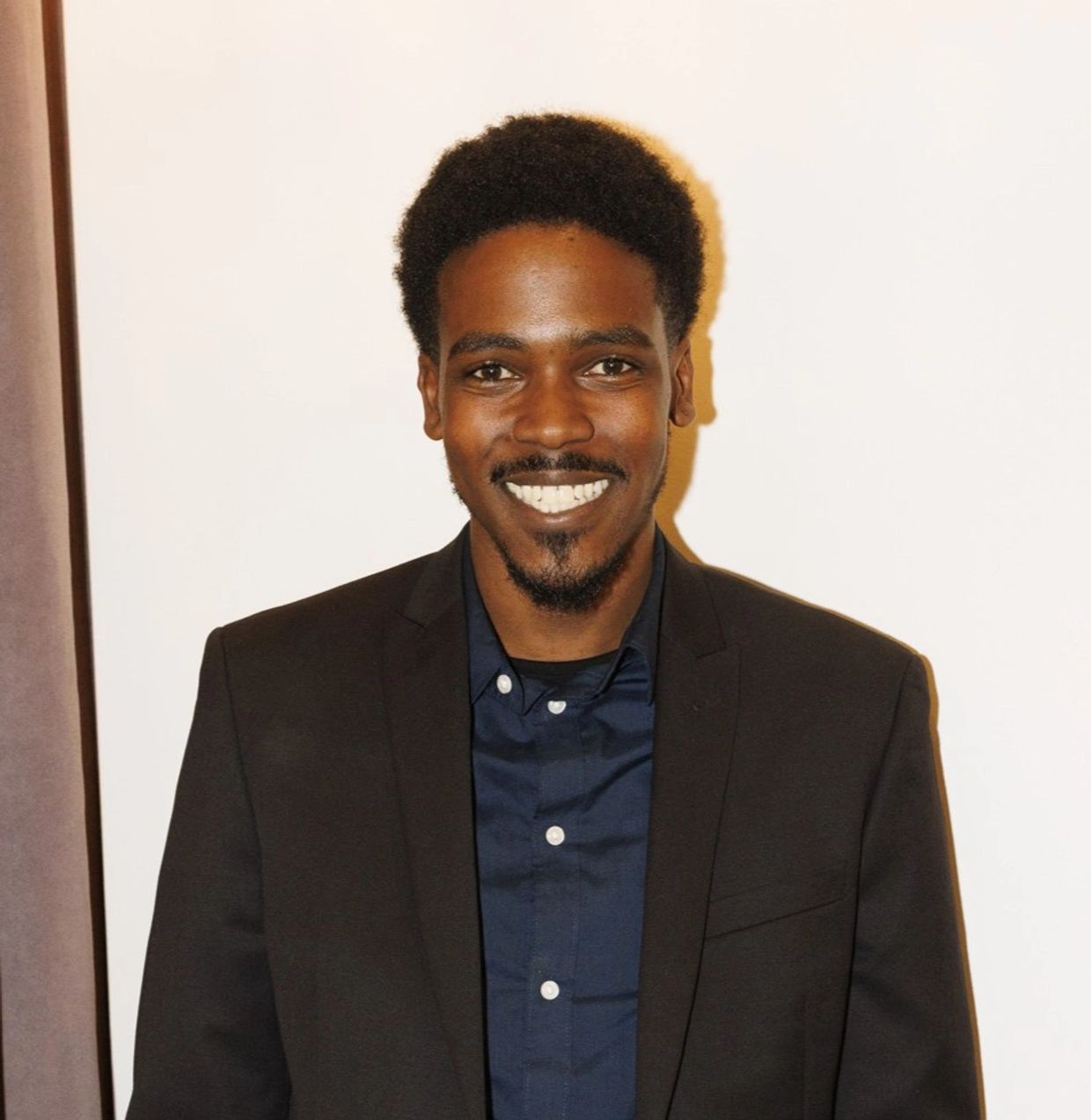 Smiling man in a dark blazer and navy shirt.