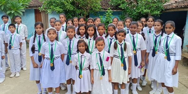School children in white uniforms with medals standing outdoors.