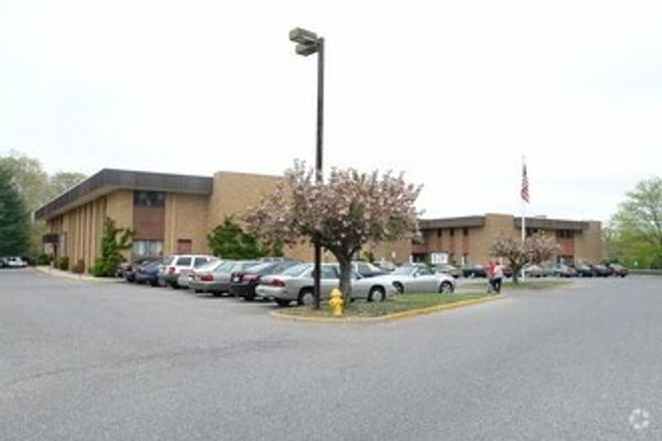 A parking lot outside a low-rise office building with cars parked and a tree in bloom.