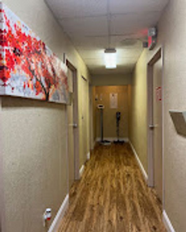 A long hallway with wooden flooring and abstract red artwork on the wall.