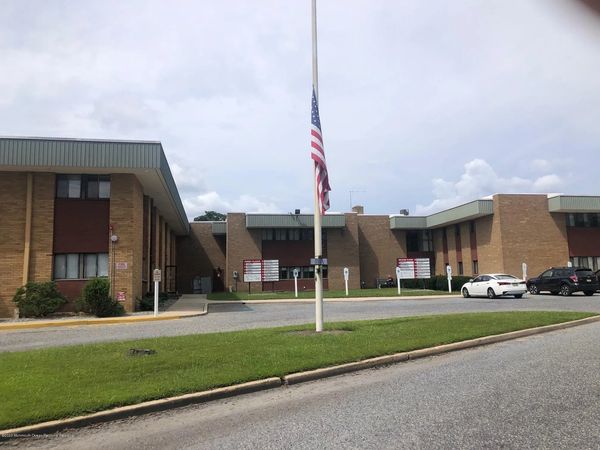 A brick institutional building with an American flag at half-mast in front.