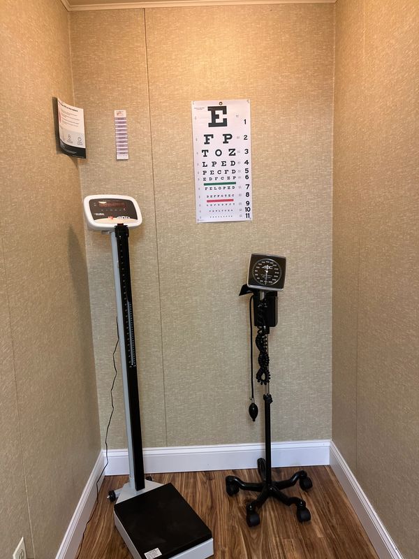 Medical examination corner with scale, sphygmomanometer, and eye chart.