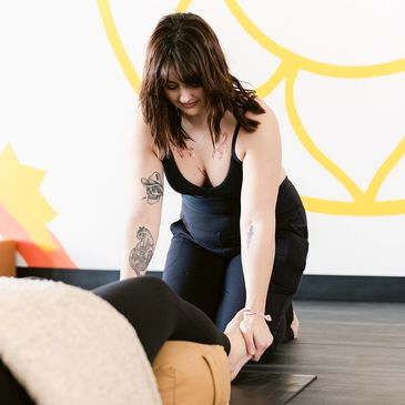 An instructor provides a gentle hands-on assist to her student who is in a reclined position.