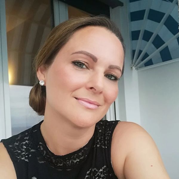 Woman smiling confidently in a black lace top.
