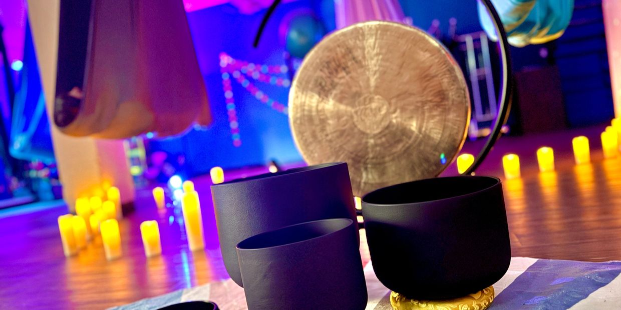 Meditative space with singing bowls and glowing candles in vibrant lighting.