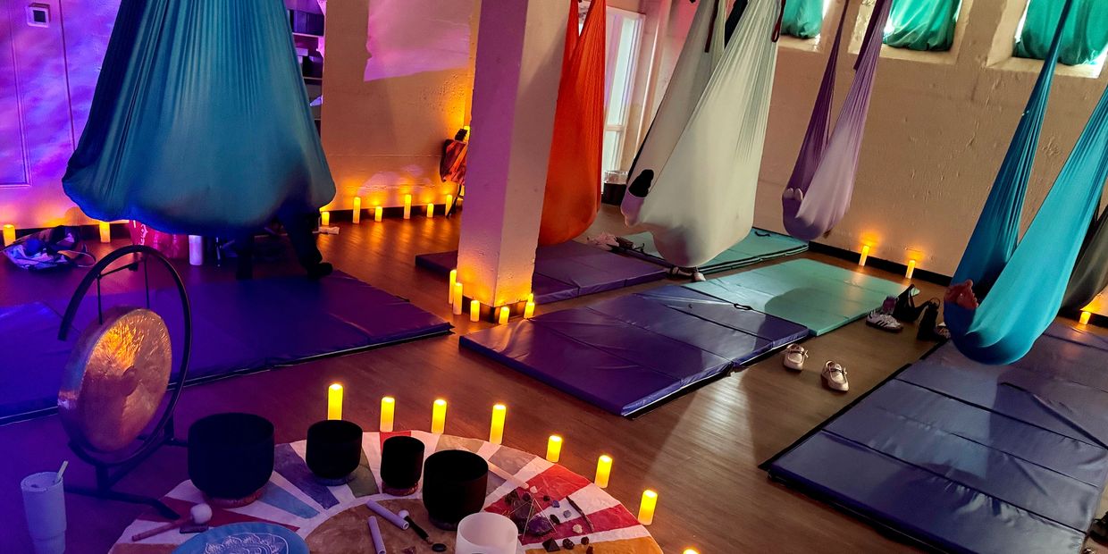 Aerial yoga hammocks with soft lighting and candles.