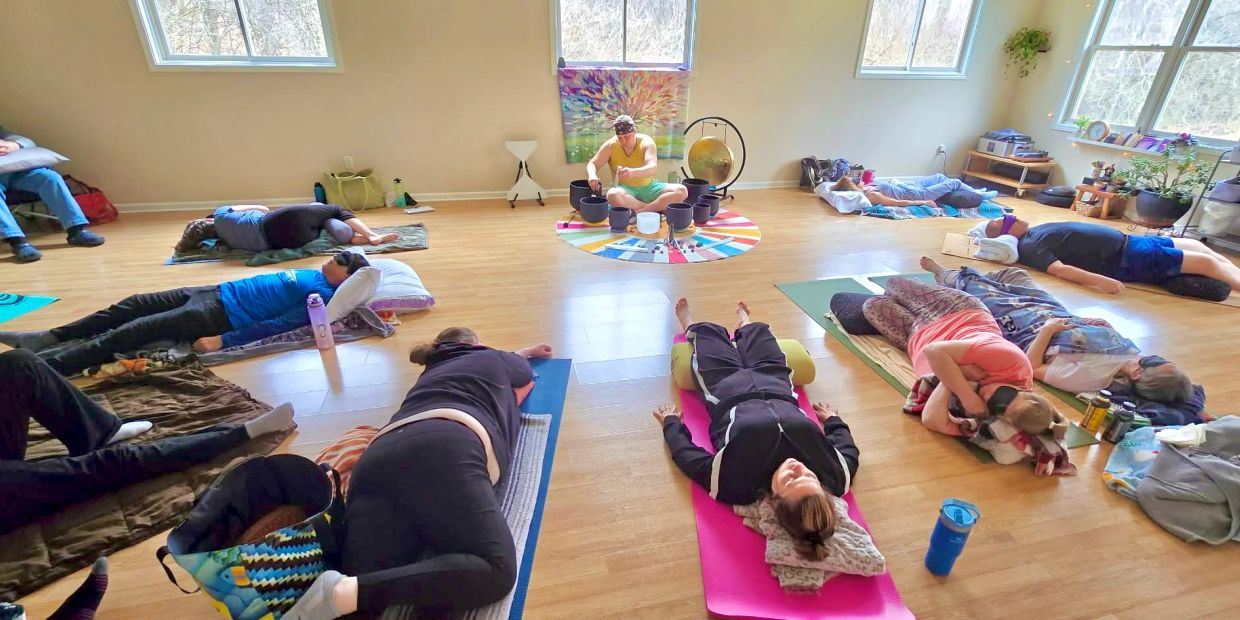 Group meditation session with sound bowls in a bright room.