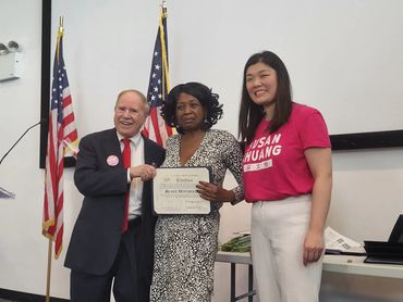 two women and a man standing next to each other holding a certificate