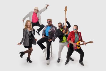 Energetic band posing with instruments and lively expressions.