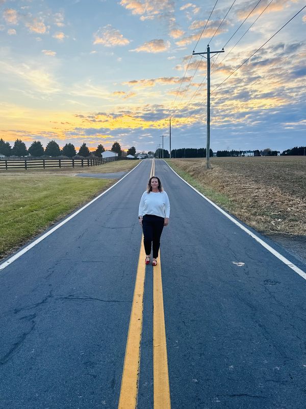 Naomi Kreske walking down the middle of the road with the sunset in the background
