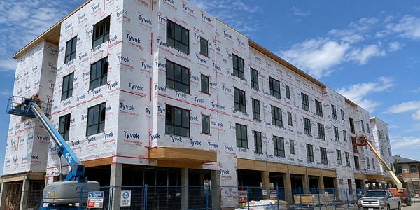 A large commercial building under construction wrapped in Tyvek.