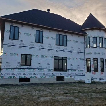 Unfinished house wrapped in Velcan building wrap at dusk.