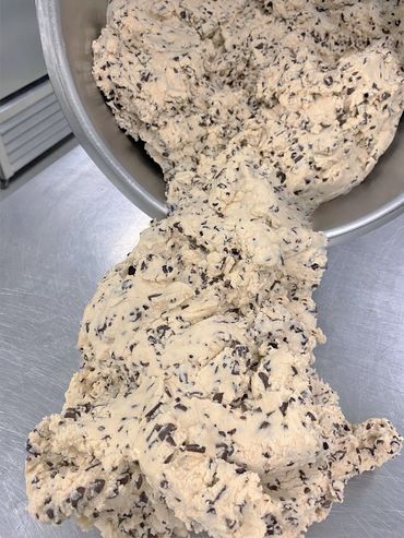 Chocolate chip cookie dough being poured from a bowl.