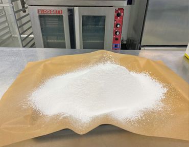 Powdered sugar spread on parchment paper in a bakery setting.