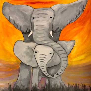 A mama and baby elephant with trunks touching, standing on green grass and orange sunset in back.