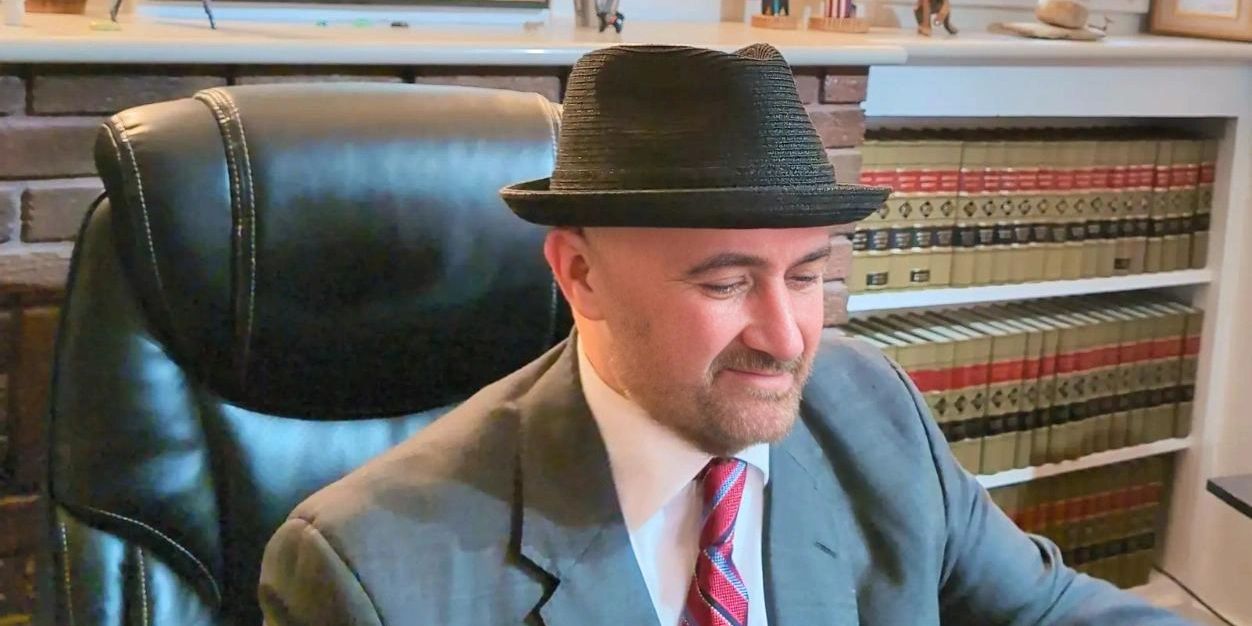 Criminal defense lawyer Barry Klopfer at his desk with a row of New Mexico Reporters behind him.