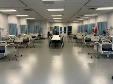 Empty simulation lab with Hill Rom Advanta 2 hospital beds with headwalls, Manikins, and overbed tables