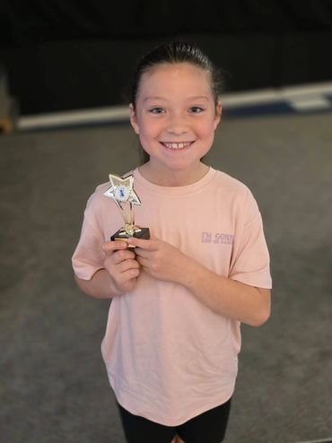 Smiling girl holding a star-shaped trophy, proud of her achievement.