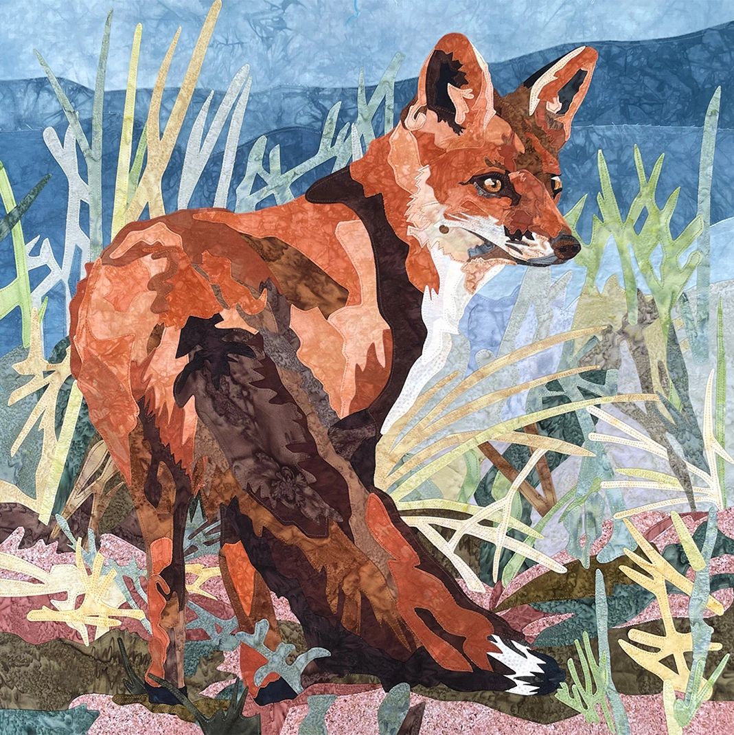 Fabric collage of a Red Fox in dune grass with blue water in the distance